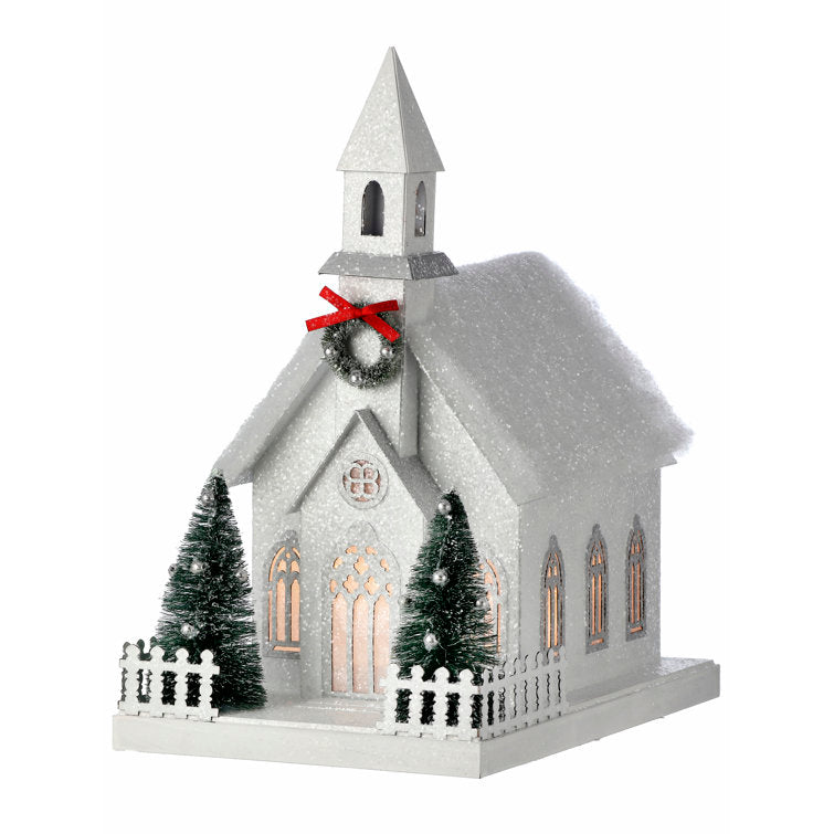 11.5-inch white sugared cardboard country church with LED lights, mini trees, and a red bow wreath.