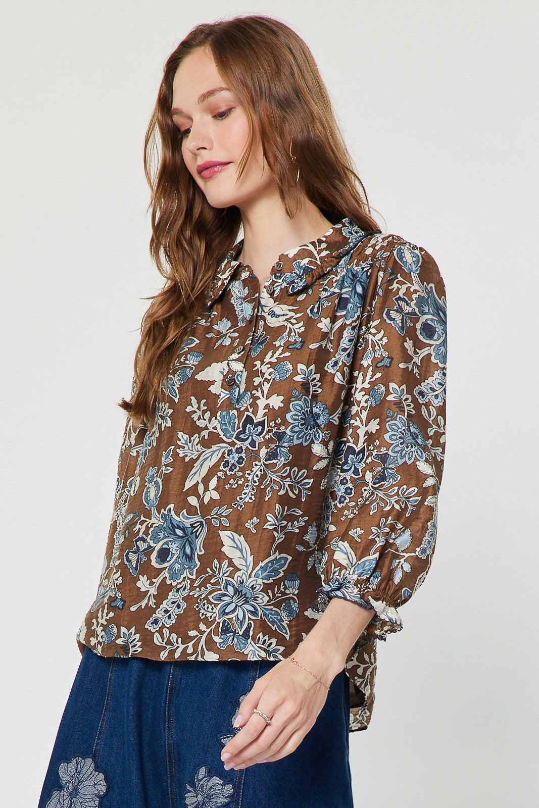 Sheer floral paisley blouse with shirt collar, ruffled detail, half placket buttons, and smocked back in Tencel blend.