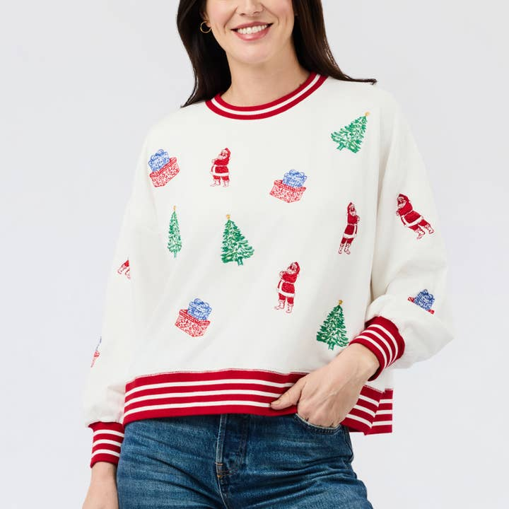 White sweatshirt with red striped trim and embroidered Christmas trees, Santas, and gifts.