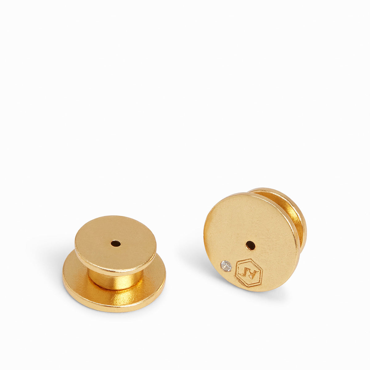 Pair of large 24K gold-plated earring backs with a signature logo and small crystal detail.