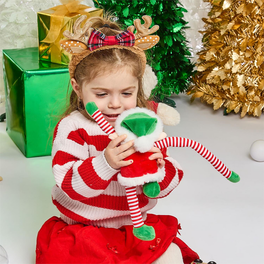 A young girl holding an Alfie the Elf plush toy with reversible candy-cane striped arms and legs.
