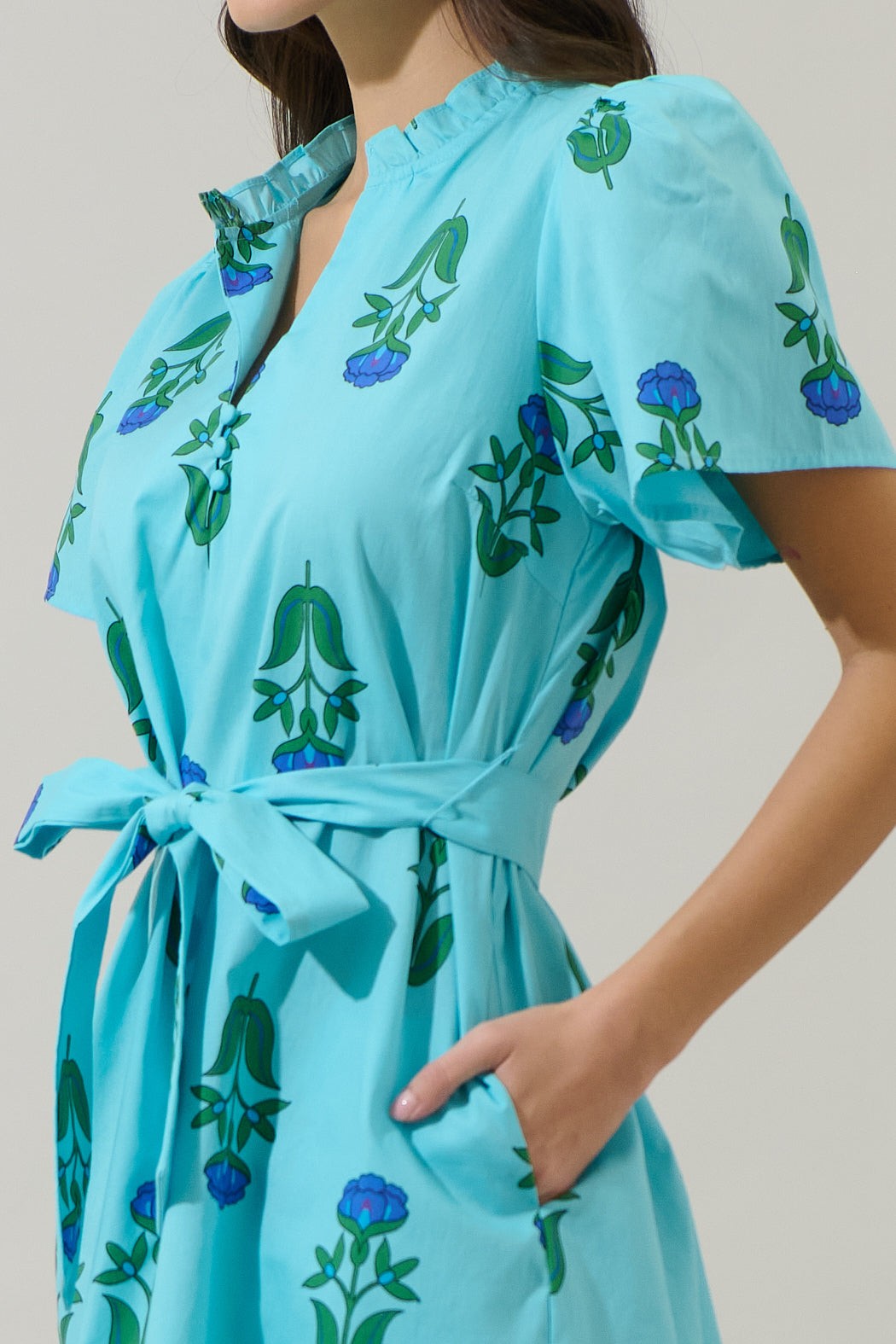 Close-up of the Amena Floral Ema Shift Mini Dress in light blue with a belted waist and split neck.