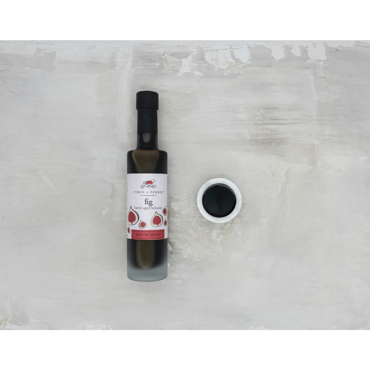 Bottle of Fig Barrel Aged Dark Balsamic vinegar with a dark liquid visible through clear glass.