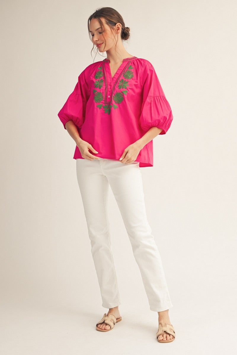 Front view of a white cotton embroidered top with balloon sleeves, notched V-neck, and front buttons.
