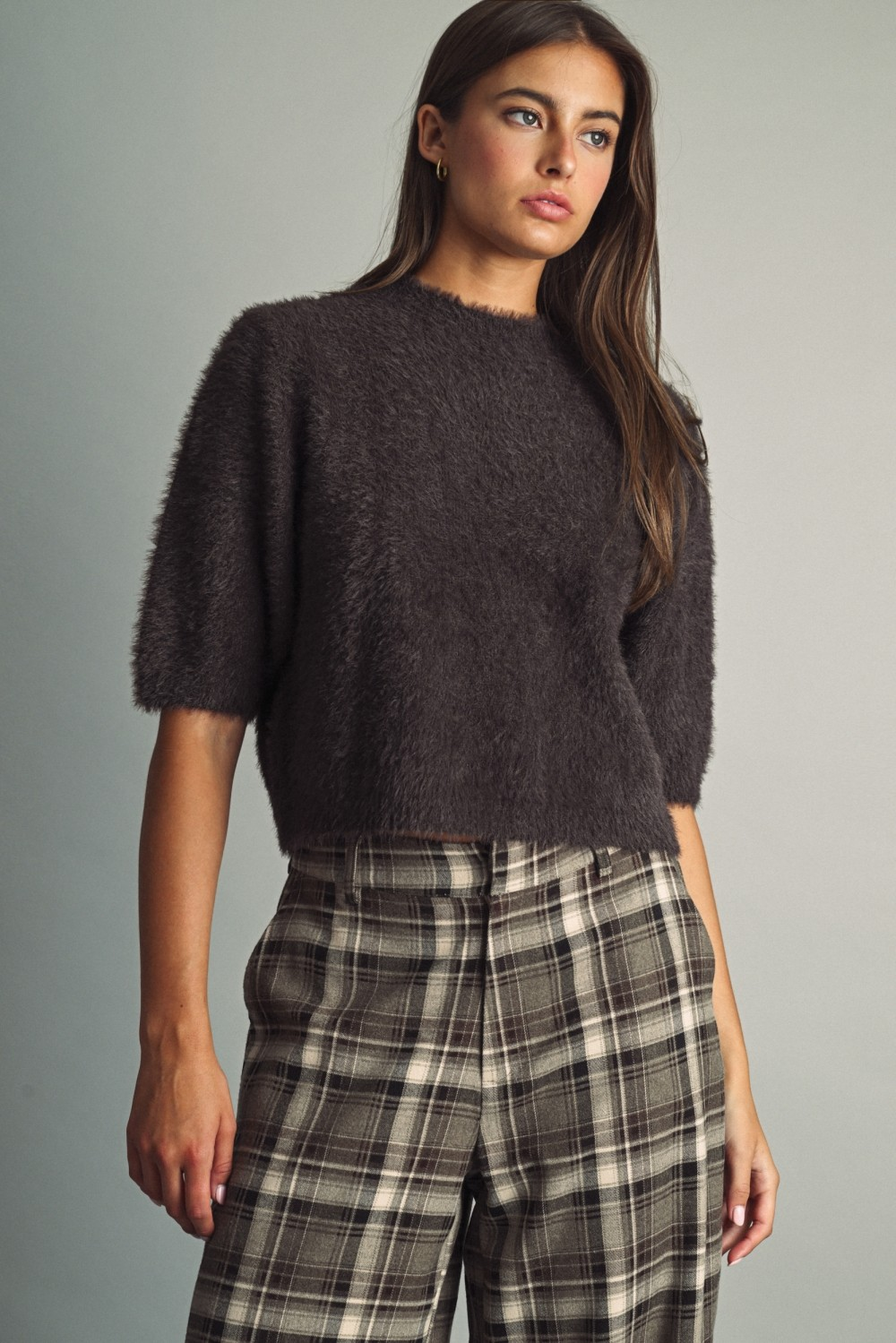 Woman wearing a chocolate brown fluffy cropped faux-fur sweater and plaid wide-leg trousers.