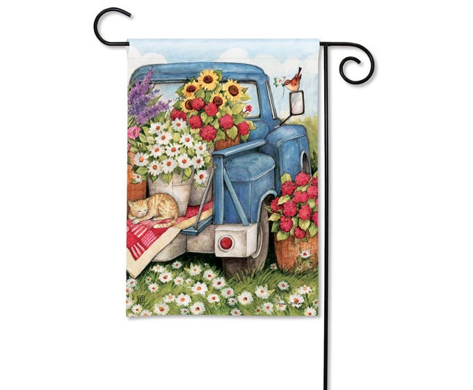 Blue garden flag with a watercolor painting of a blue truck filled with sunflowers, daisies, and red flowers, a sleeping cat, and a bird.