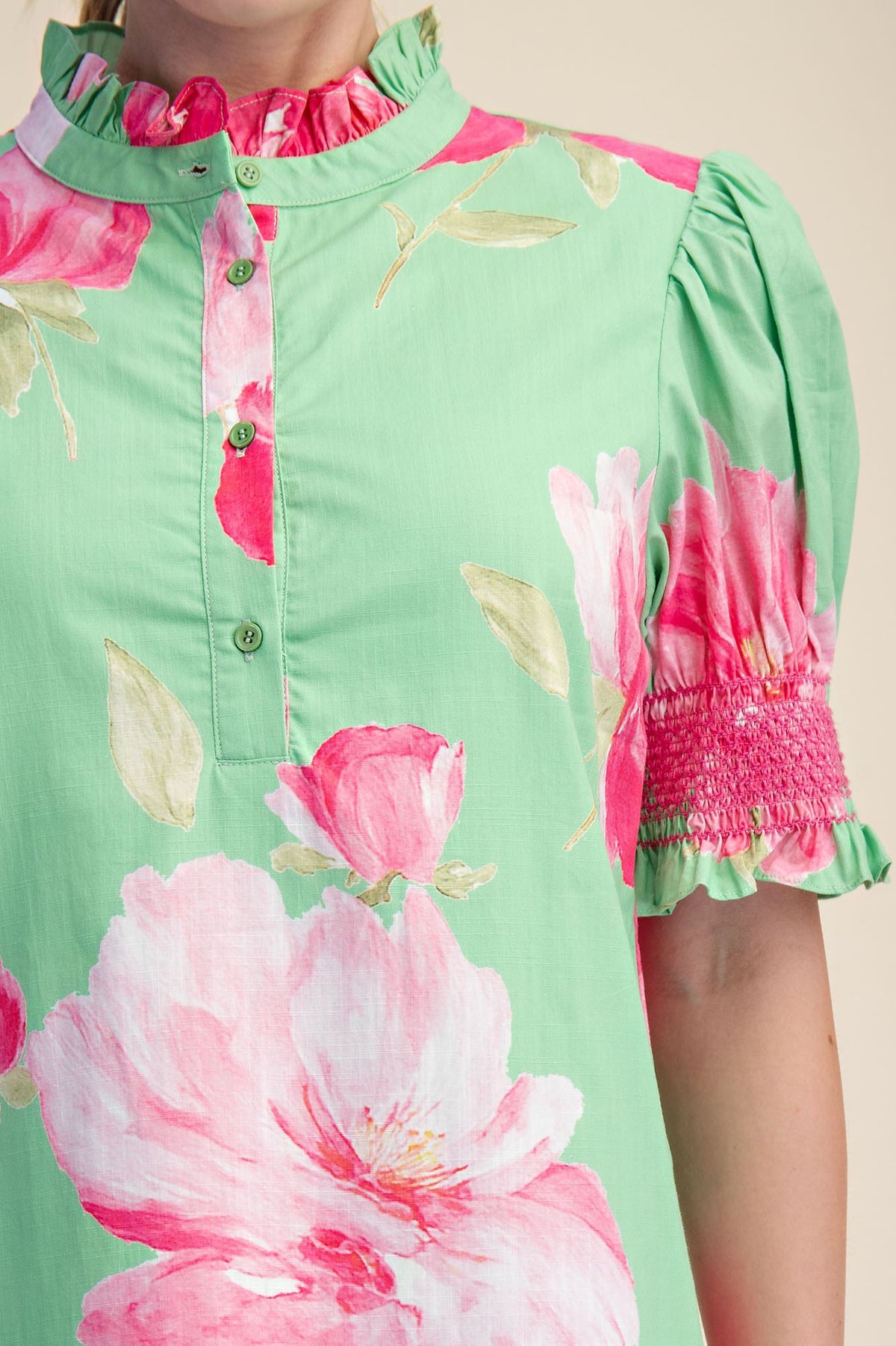 Close-up of a green floral midi dress with a ruffled neck, button placket, and smocked puff sleeves.