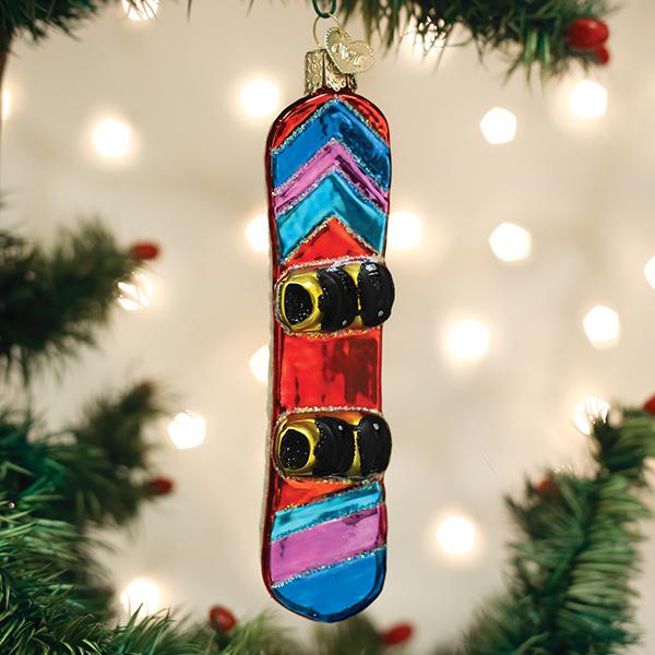 Glass snowboard ornament with colorful stripes and black bindings hanging on a Christmas tree.