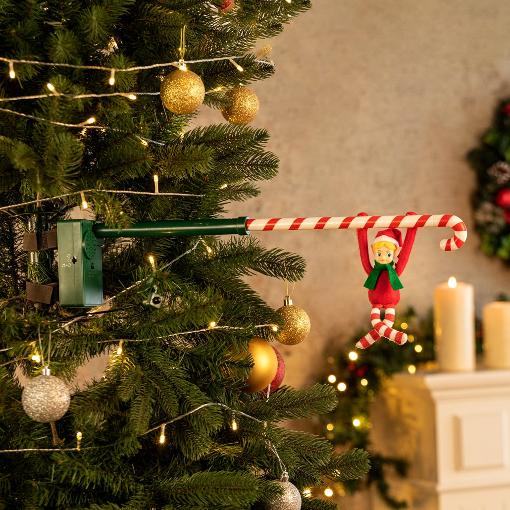 Acrobat elf toy hanging from a candy cane pole attached to a Christmas tree.