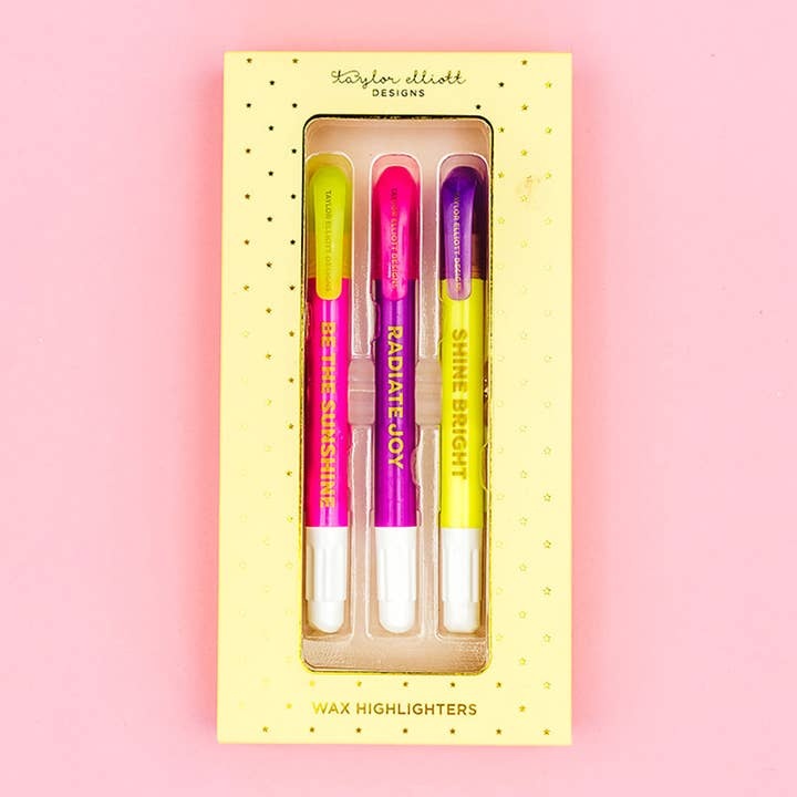Gift box containing six wax highlighters in yellow, purple, pink, orange, green, and blue with motivational phrases.