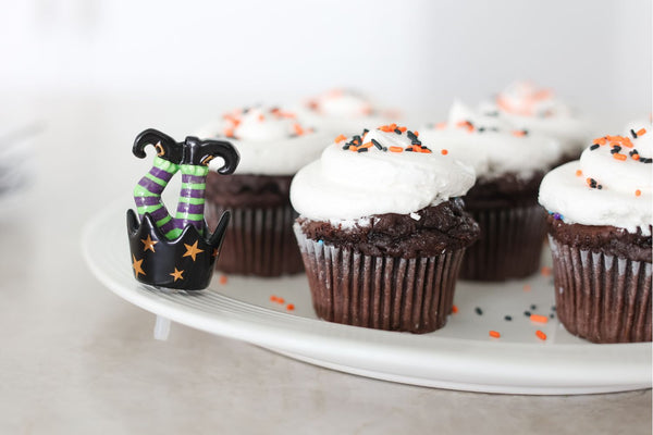Halloween cupcake topper with witch legs in striped tights and black boots.