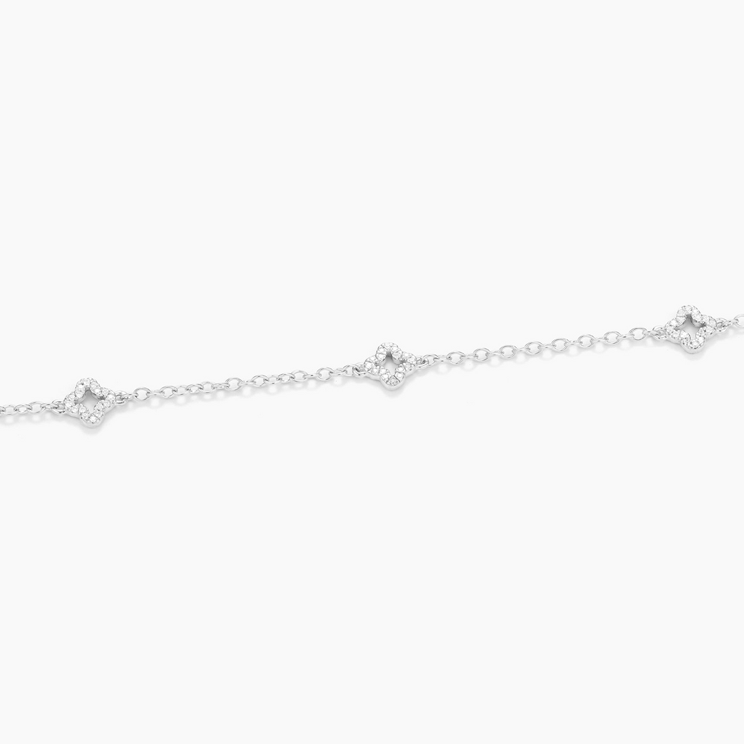 Close-up of a silver diamond station chain bracelet with three clover-shaped diamond charms.