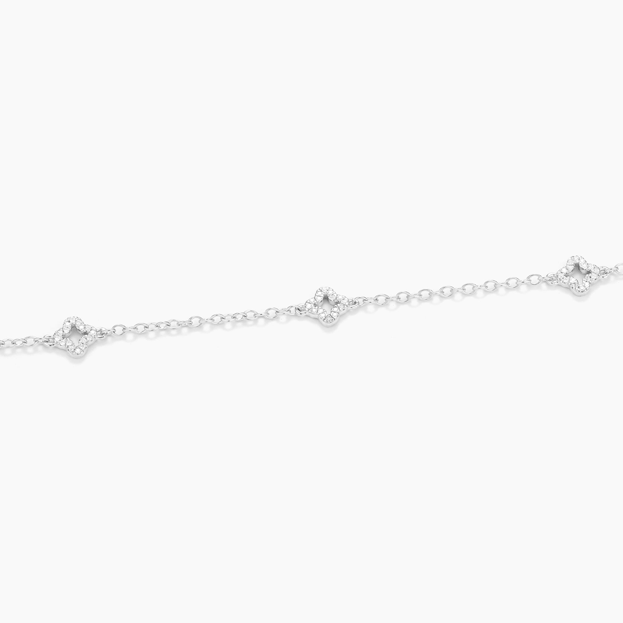 Close-up of a silver diamond station chain bracelet with three clover-shaped diamond charms.
