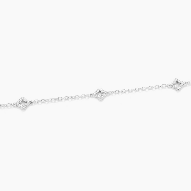 Close-up of a silver diamond station chain bracelet with three clover-shaped diamond charms.