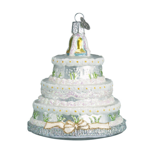 White ceramic Christmas ornament shaped like a tiered wedding cake with green holly accents.