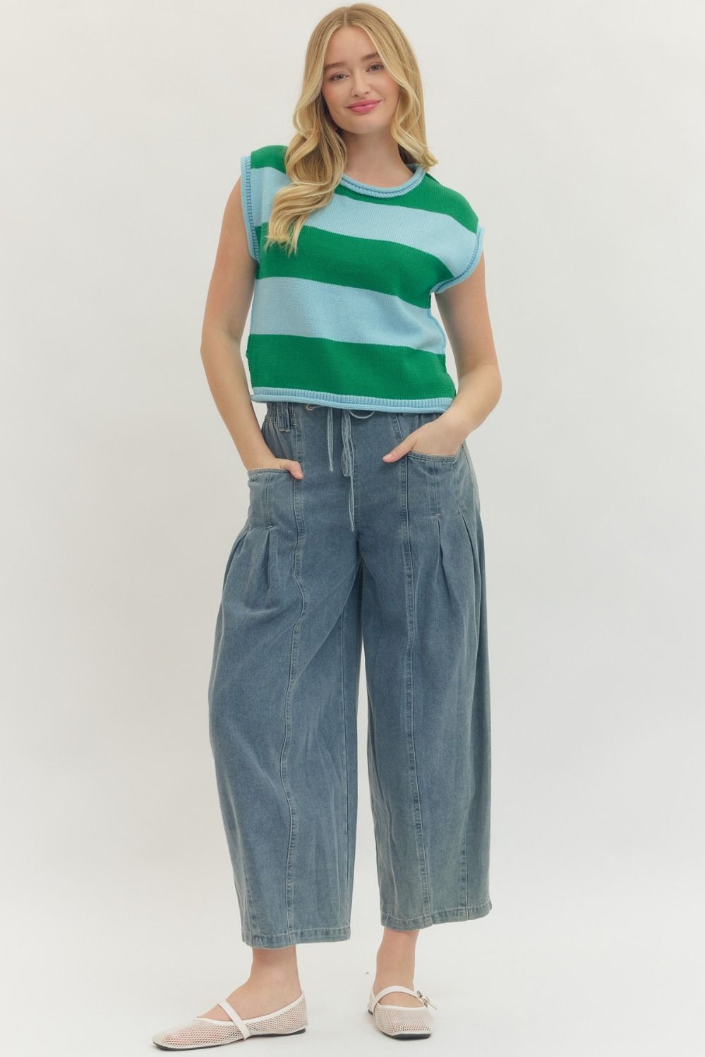 Woman wearing a Kathleen Striped Cap Sleeve Top in green and light blue with wide-leg denim pants.