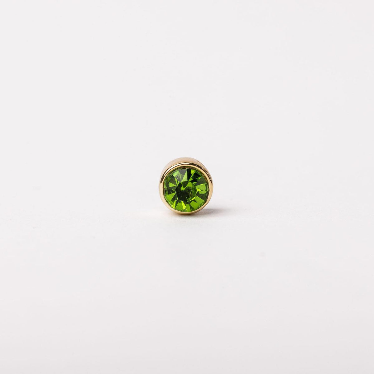 Gold-tone stud earring featuring a round, faceted lime green gemstone in a bezel setting.