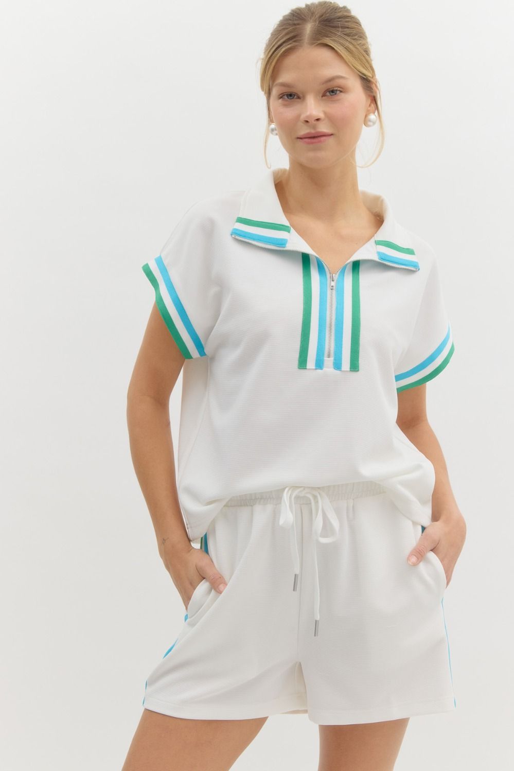 Woman wearing white Jasmine Jersey Knit Shorts with blue and green side stripes and matching top.
