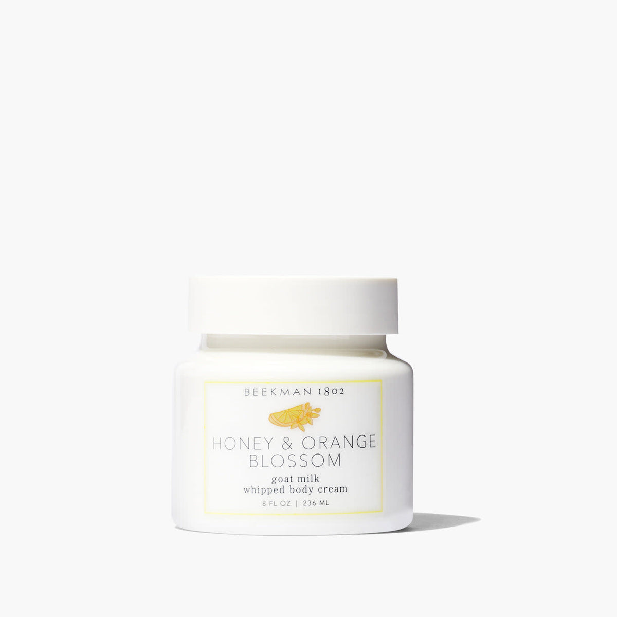 Whipped body cream jar with honey-orange-blossom color visible through clear packaging