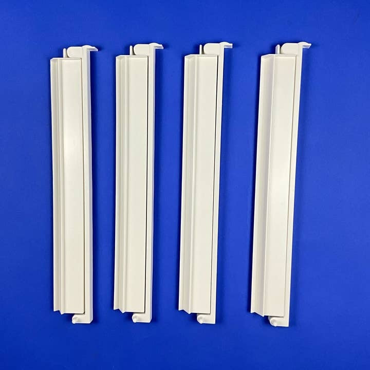 Four white acrylic American Mahjong racks with attached pushers stacked together.
