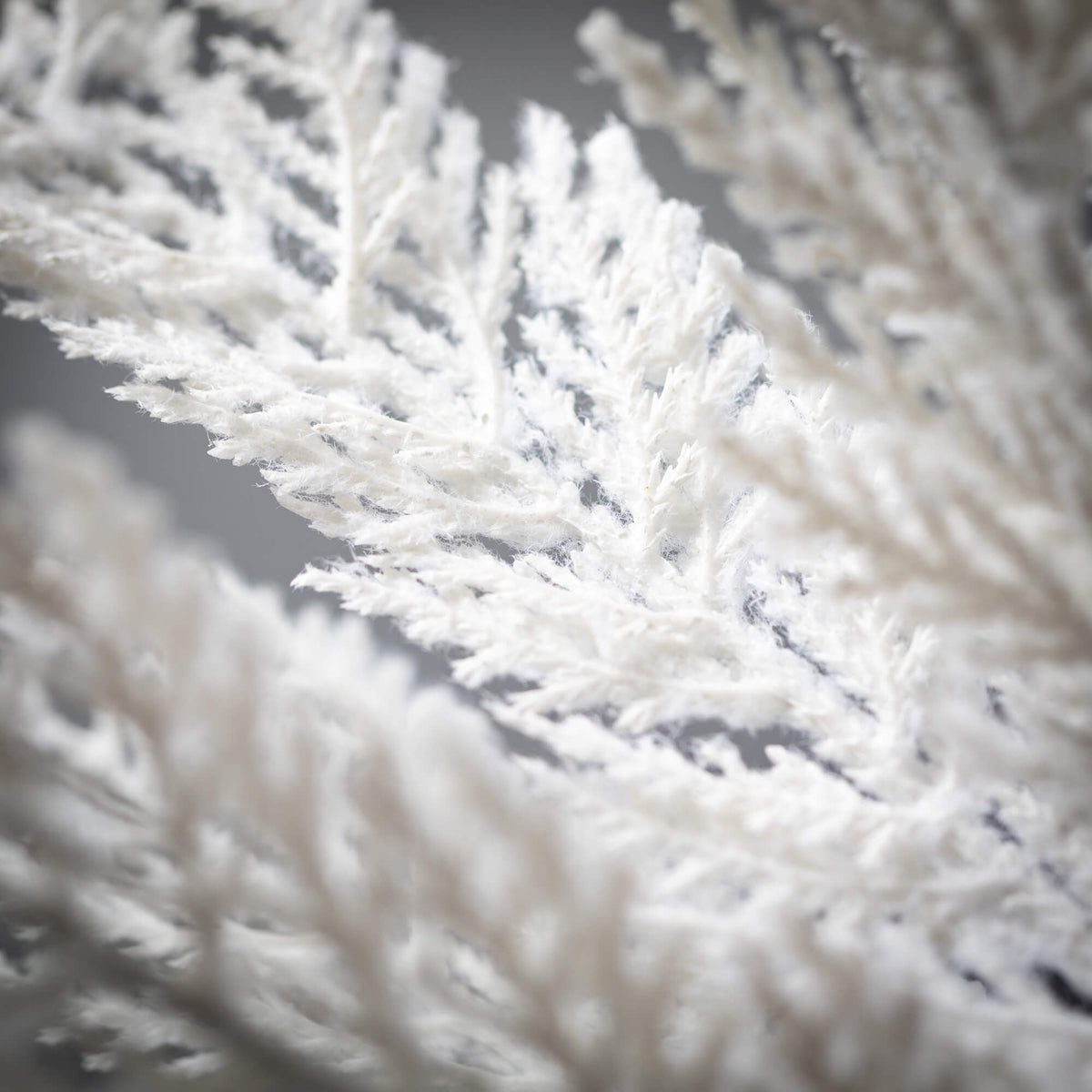 White plastic cypress spray ornament with realistic pine branch texture.