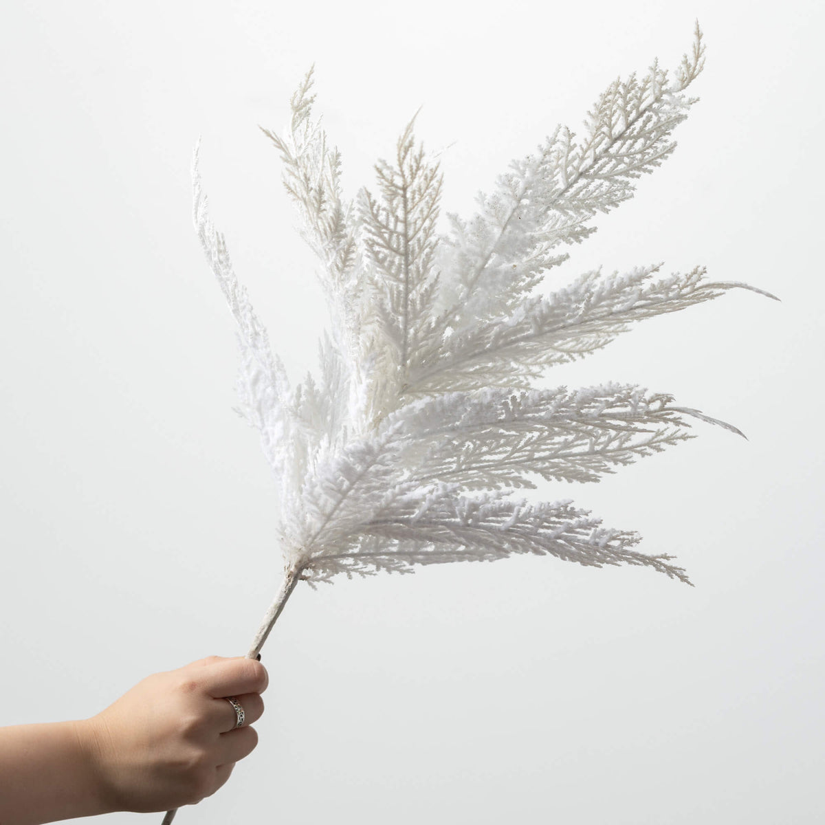 White plastic cypress spray with a natural branch-like silhouette designed for holiday mantel decor.