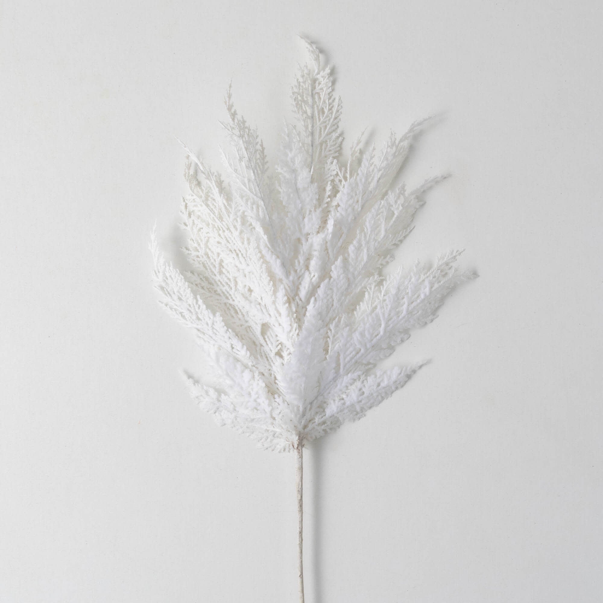 White plastic cypress spray with a natural branch-like silhouette designed as artificial Christmas tree decor.