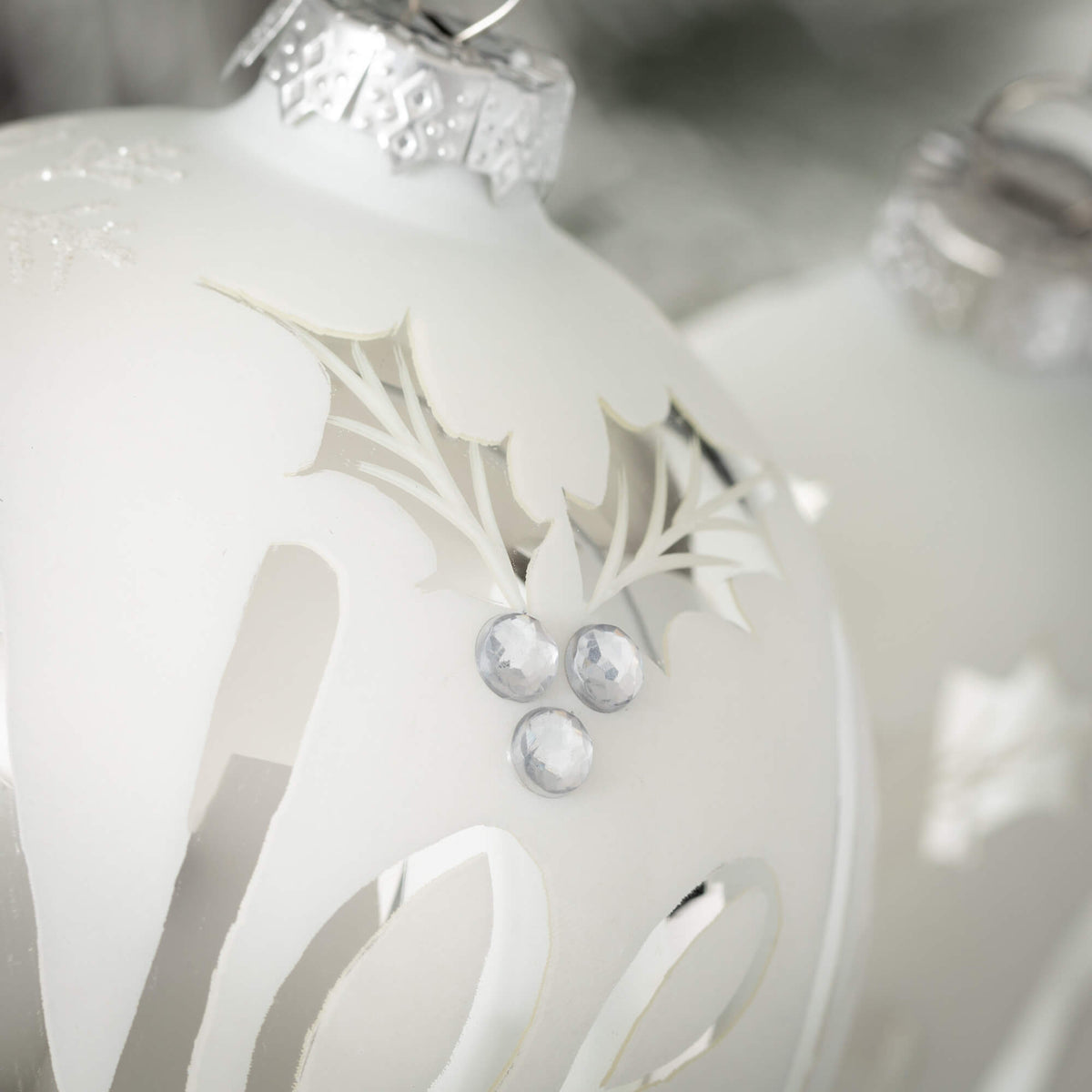 Glass Christmas ornament with white background and shiny silver Noel lettering