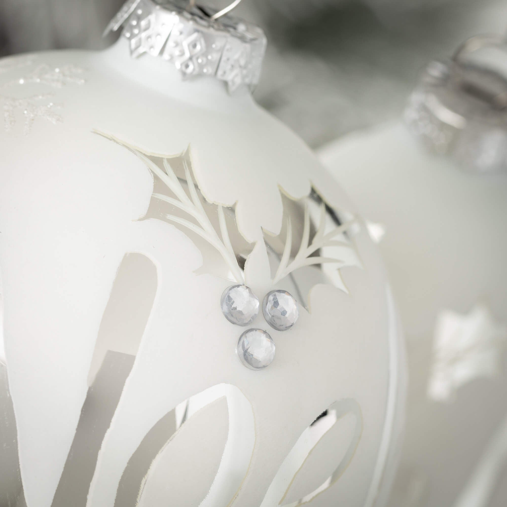 Glass Christmas ornament with white background and shiny silver Noel lettering