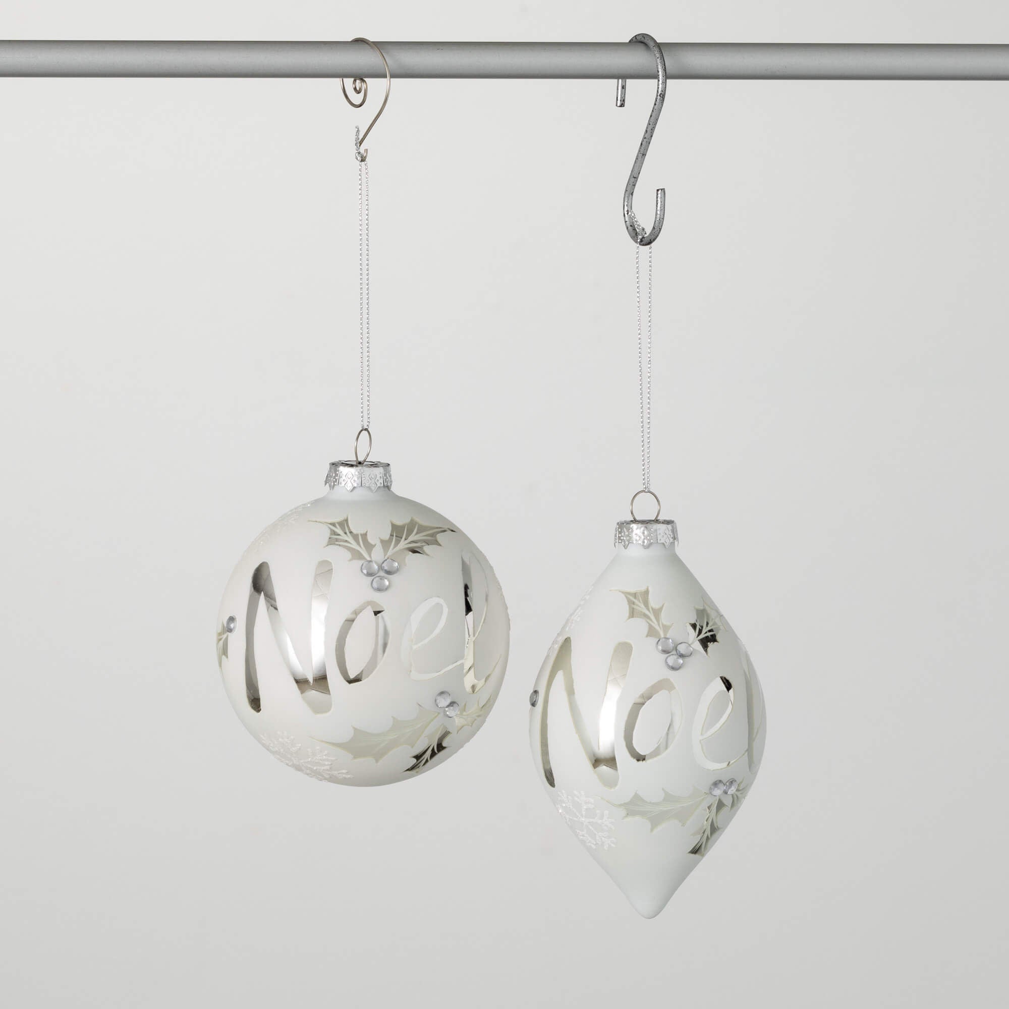 Glass Christmas ornament with white background and shiny silver Noel lettering