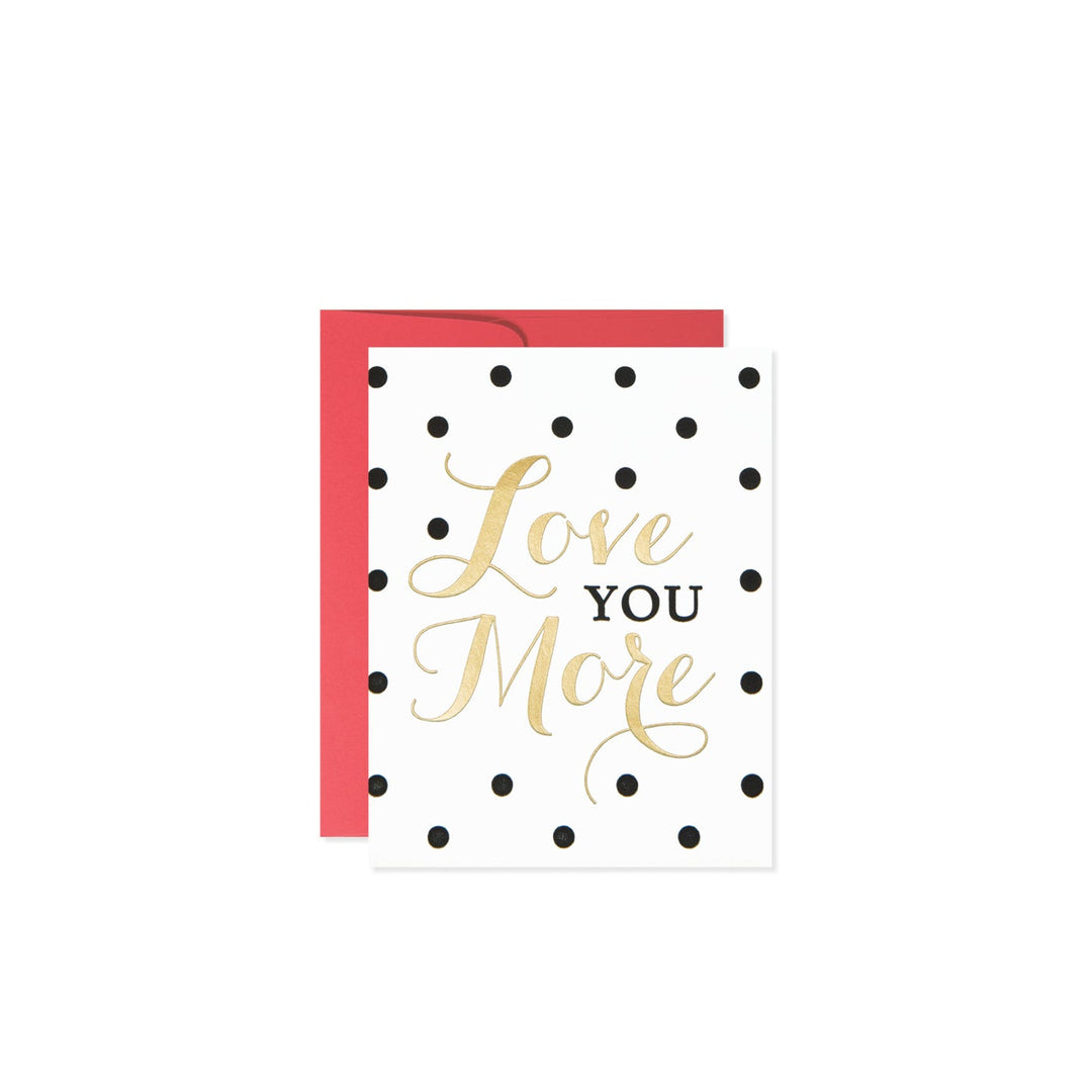 White greeting card with black polka dots and gold text that reads 'Love You More'.