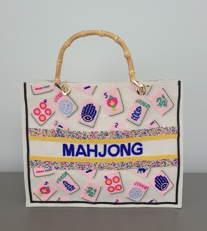 Tiana Design Mahjong Tote in pink with hand-beaded tiles, bamboo handle, and blue text.