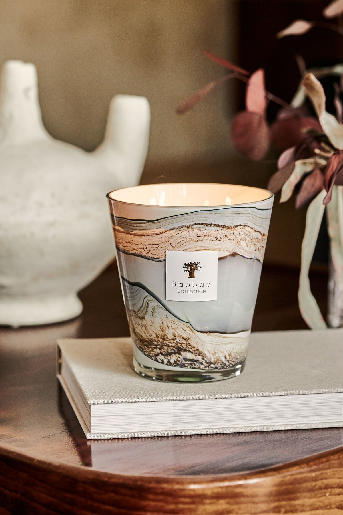 Glass candle vessel with organic celadon green to blue-gray wax lines featuring saffron and myrrh fragrance.