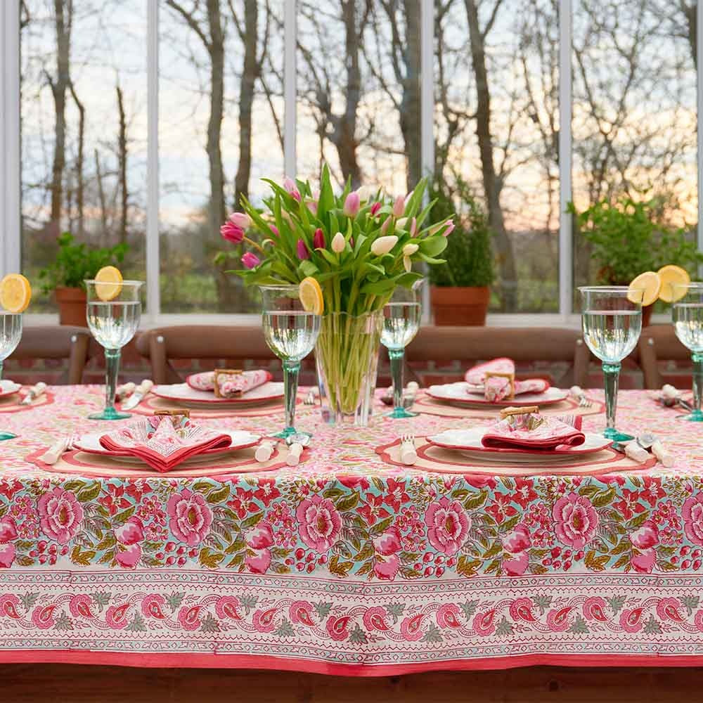 White cotton tablecloth with a wildflower garden print featuring pink blooms and lime green accents.