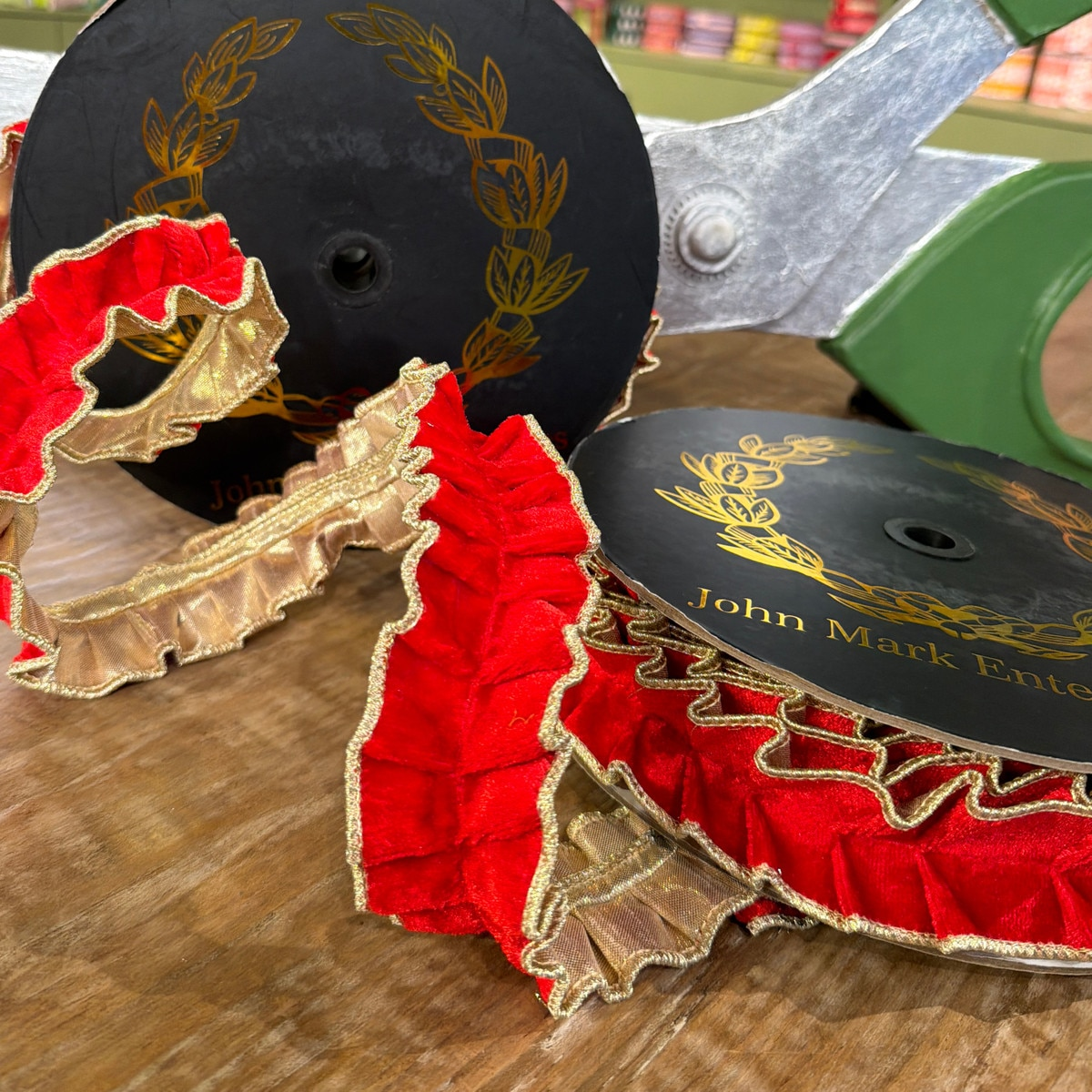 Red velvet pleated ribbon with metallic gold dupion trim on black spools.