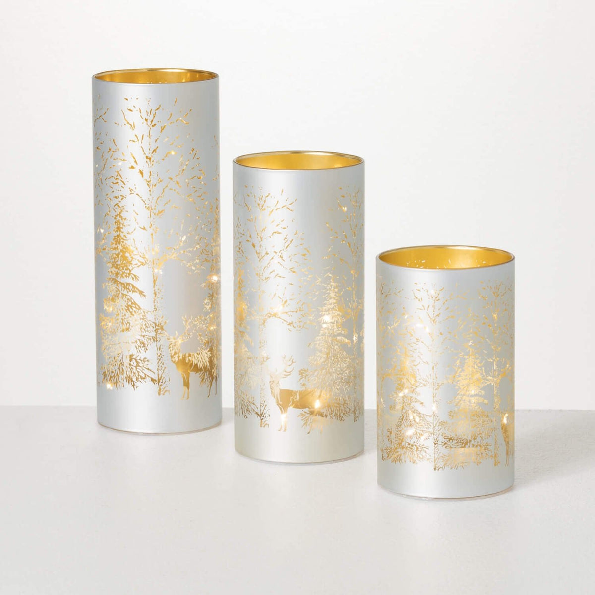 Set of three lighted cylinder ornaments in winter scene designs with gold accents.