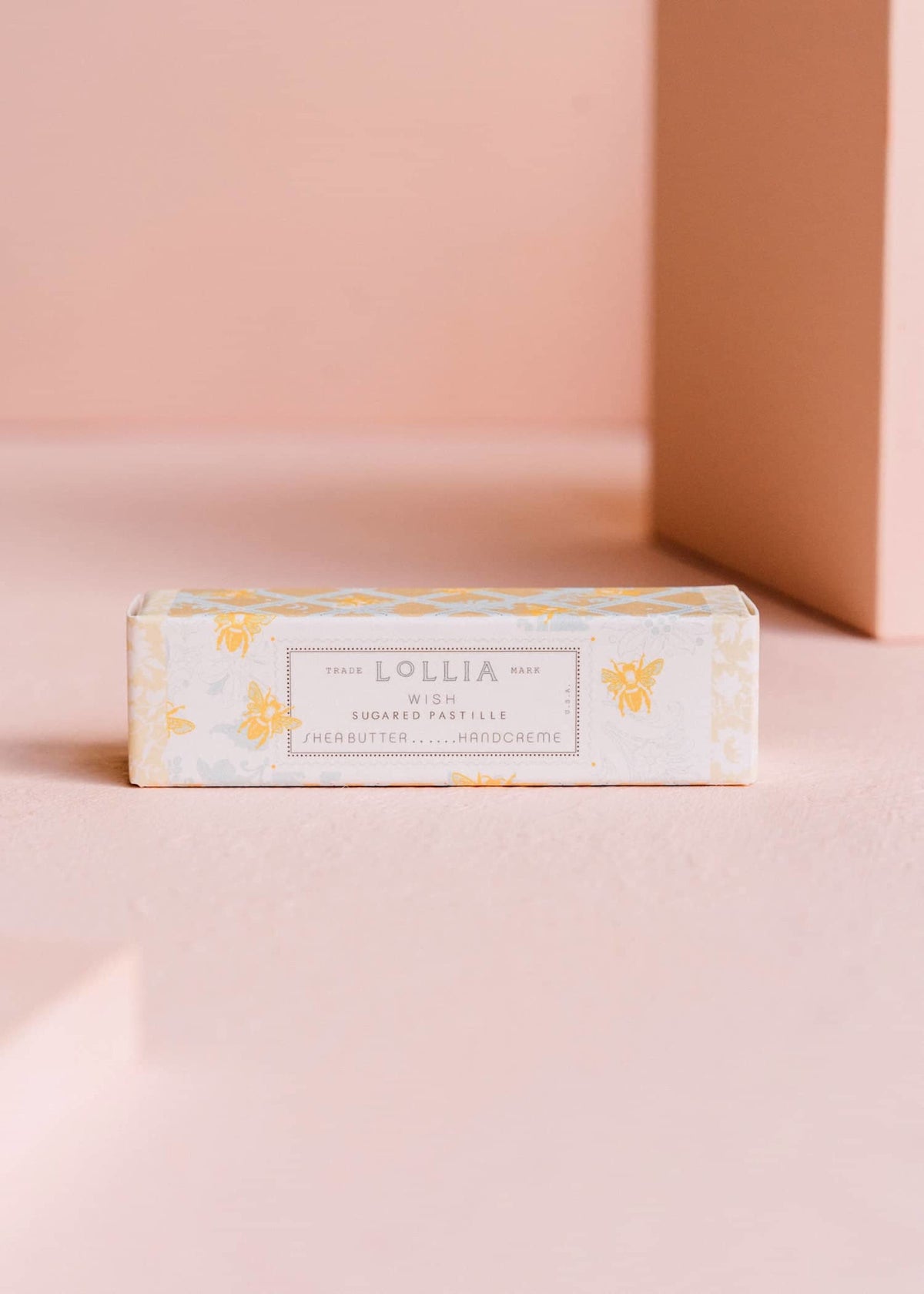 Petite Wish hand cream in golden bees over blue French foulard pattern with understated floral vines.