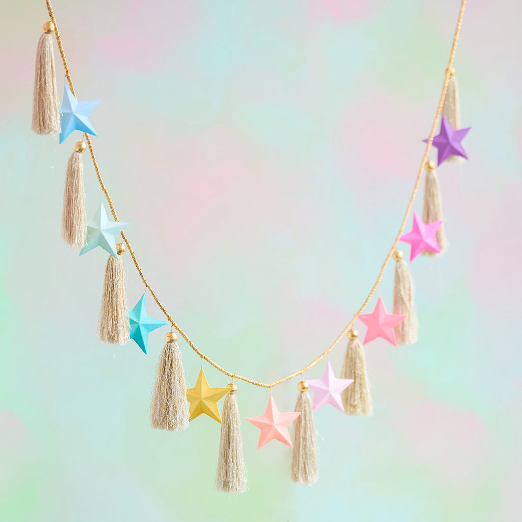 Rainbow Star Garland with hand-painted colorful paper mache stars and jute tassels on a gold cord.