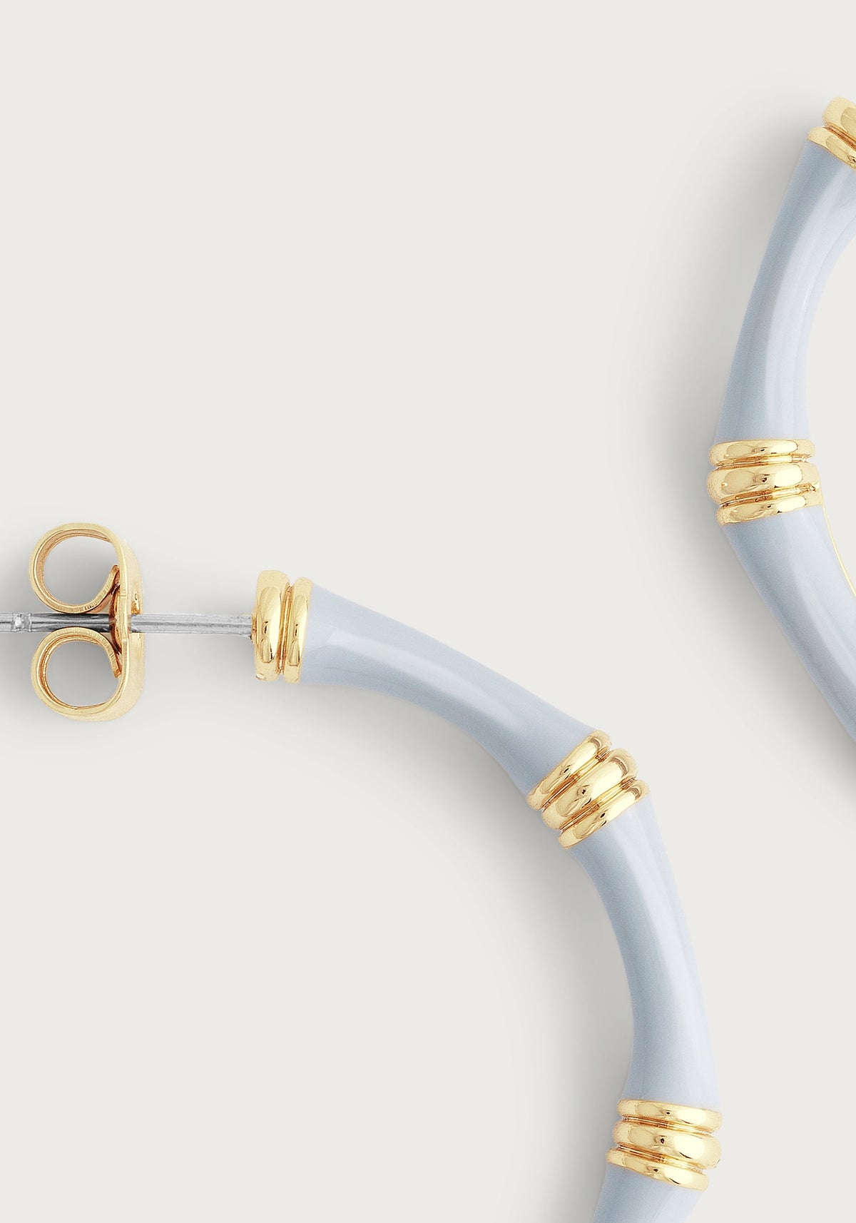 Close-up of light blue enameled bamboo-style hoop earrings with 18K gold-plated brass accents.