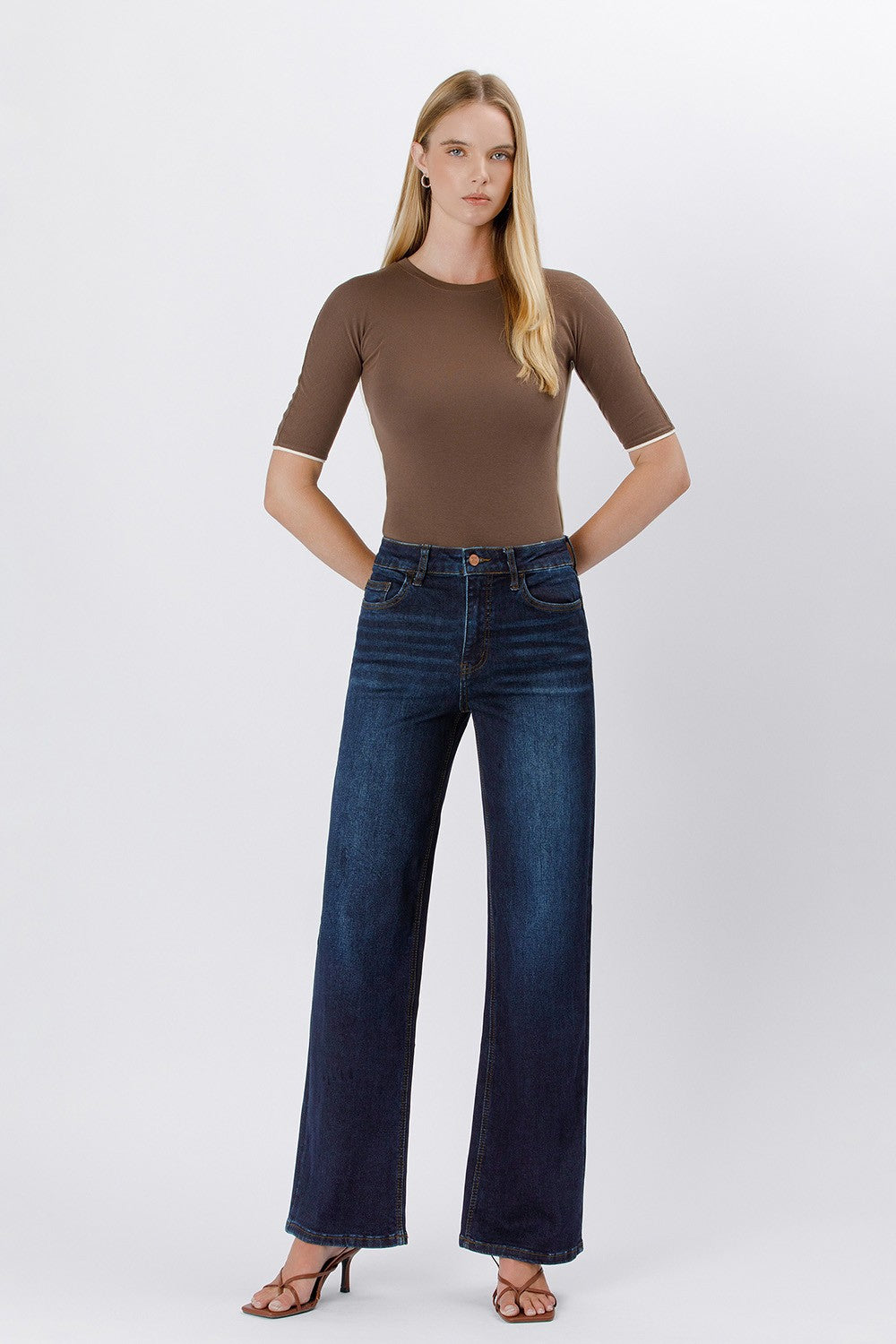 Woman wearing Trixie 90’s vintage super high rise dark wash loose jeans and a brown top.