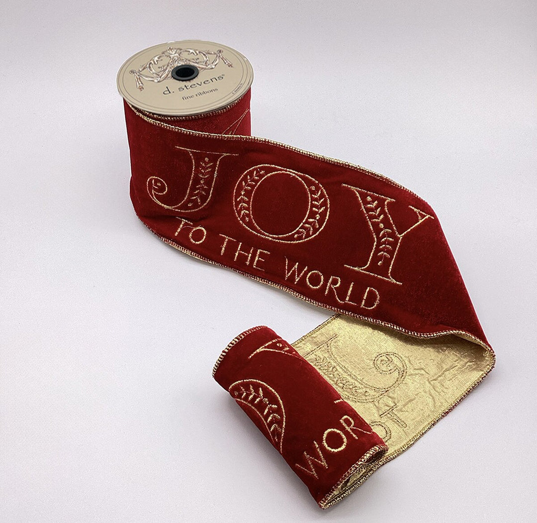 4 inch red velvet ribbon with gold embroidered Joy to the World text on a spool.