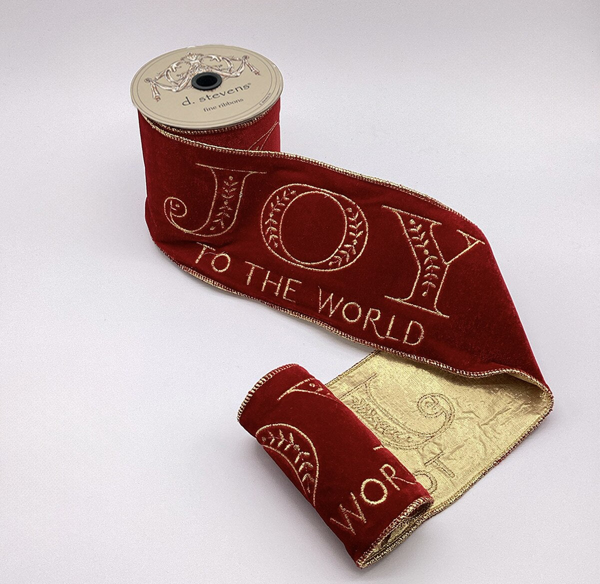 4 inch red velvet ribbon with gold embroidered Joy to the World text on a spool.