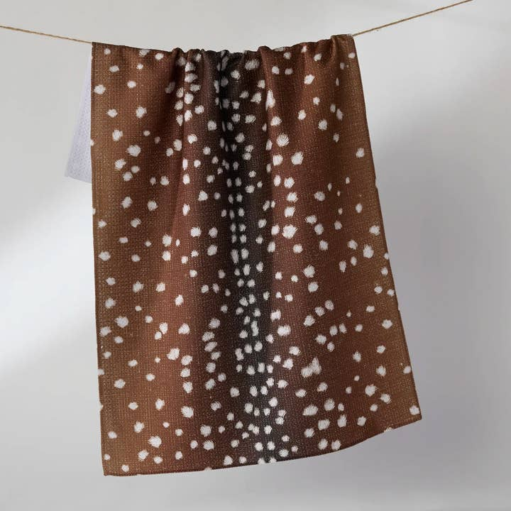 Everyday Tea Towel with a brown and white spotted deer print hanging on a clothesline.