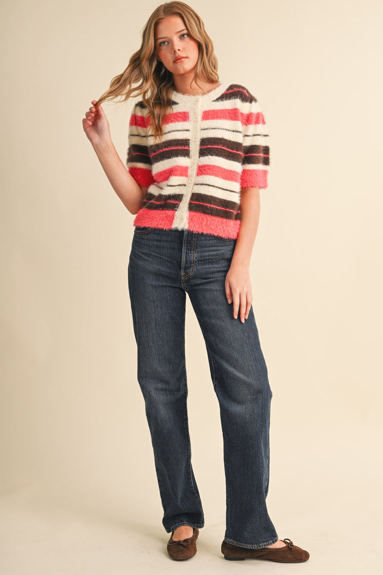 Woman wearing a fuzzy striped short puff sleeve sweater cardigan in pink, white, and brown.