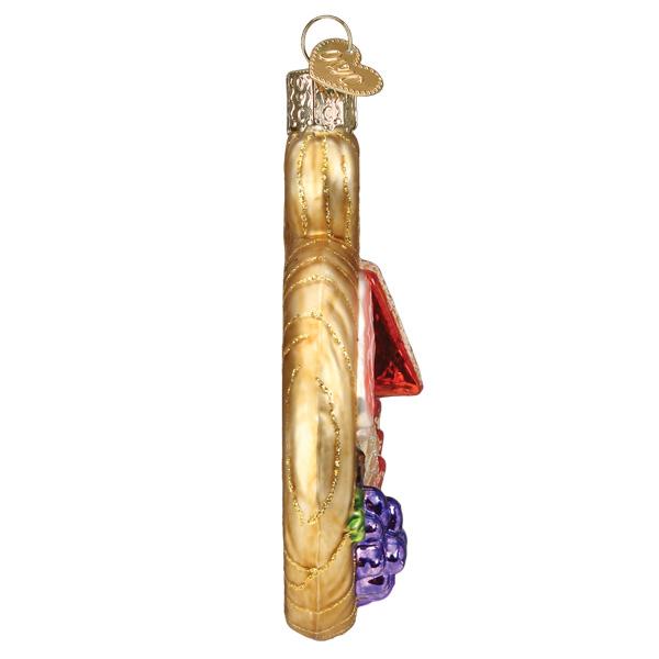 Side view of a glass charcuterie board ornament with gold glitter accents and purple grapes.