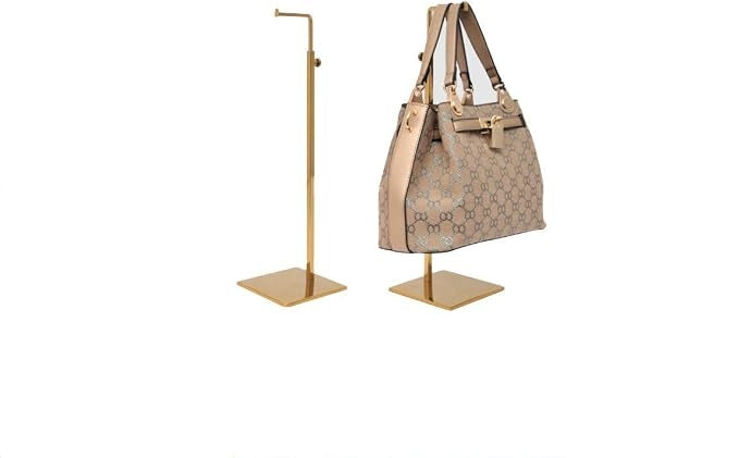 Two gold-plated handbag display stands, one empty and one holding a patterned tote bag.
