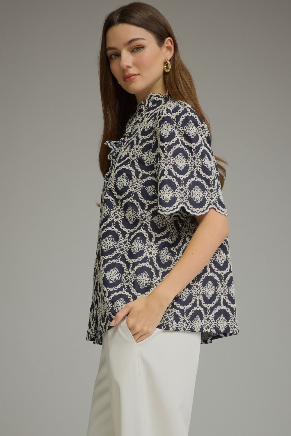 Woman wearing the Amalia navy blue geometric embroidered top with short puff sleeves.