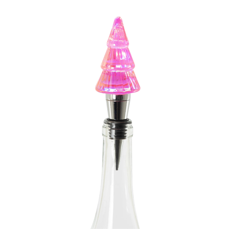 Lit pink glass Christmas tree bottle stopper with a metal base inserted into a clear glass bottle.