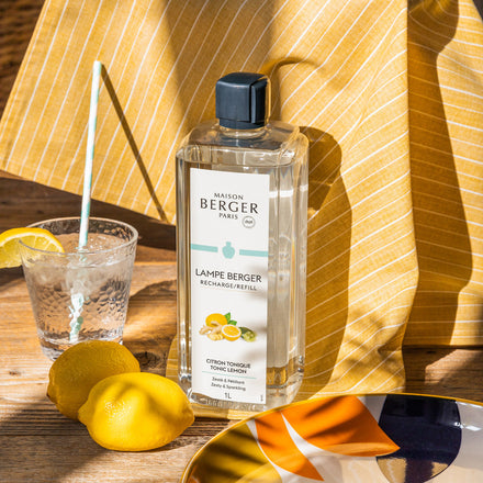 1L Maison Berger Paris Lampe Berger refill bottle in Tonic Lemon scent on a wooden table with lemons.