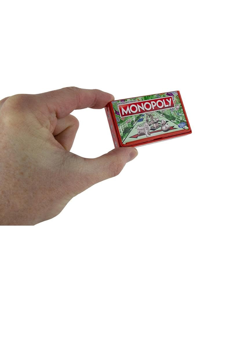 Pocket-sized Monopoly game board with miniature tokens, dice, houses, hotels, and money inside a compact storage box.